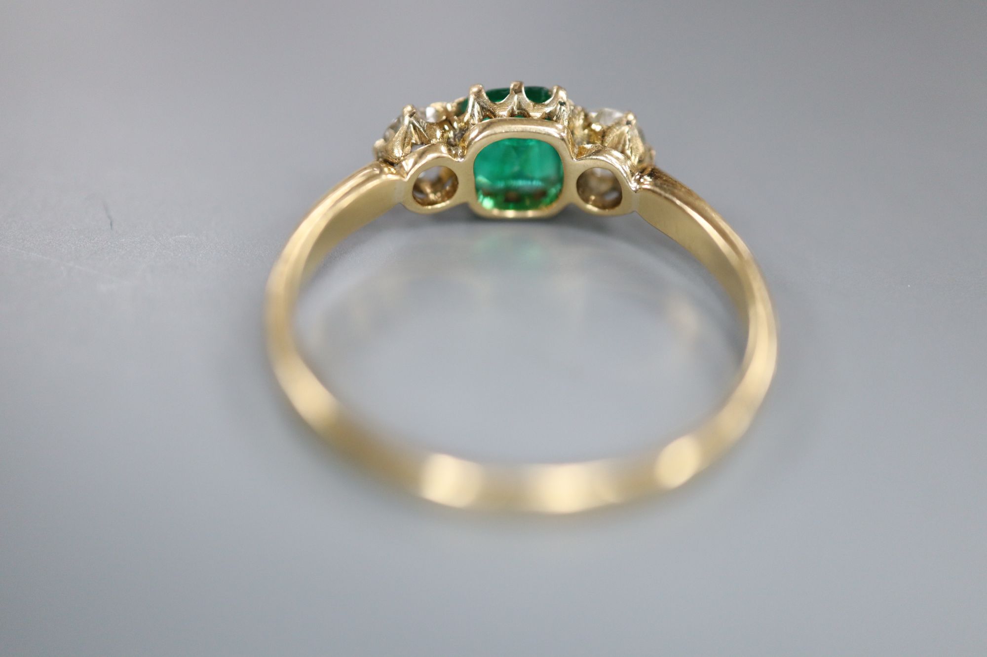 A yellow metal, emerald and diamond three stone ring, size Q, gross 2.3 grams.
